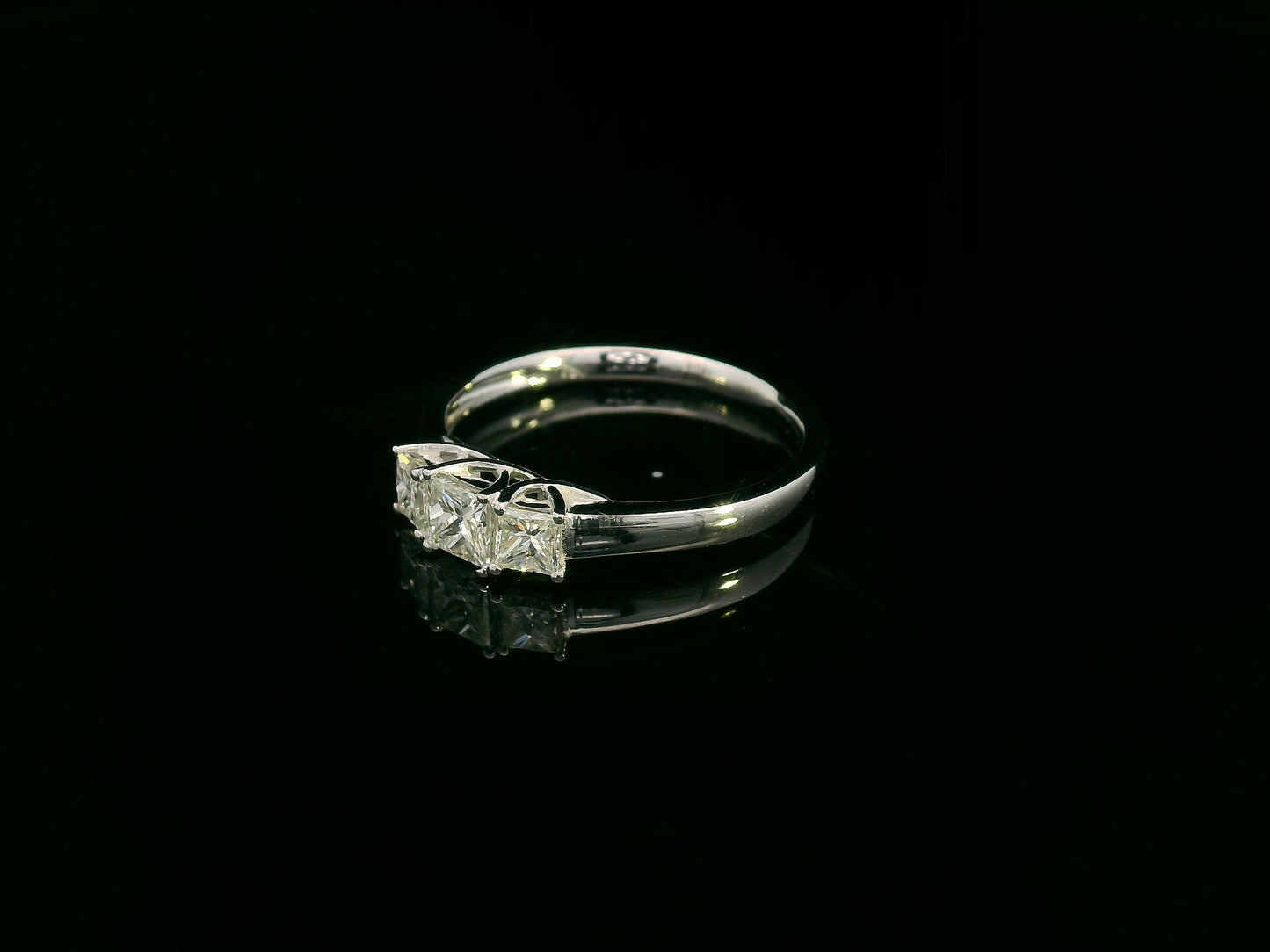 18k white gold trilogy ring with three princess-cut diamonds, total 0.66 ct, modern classic design.