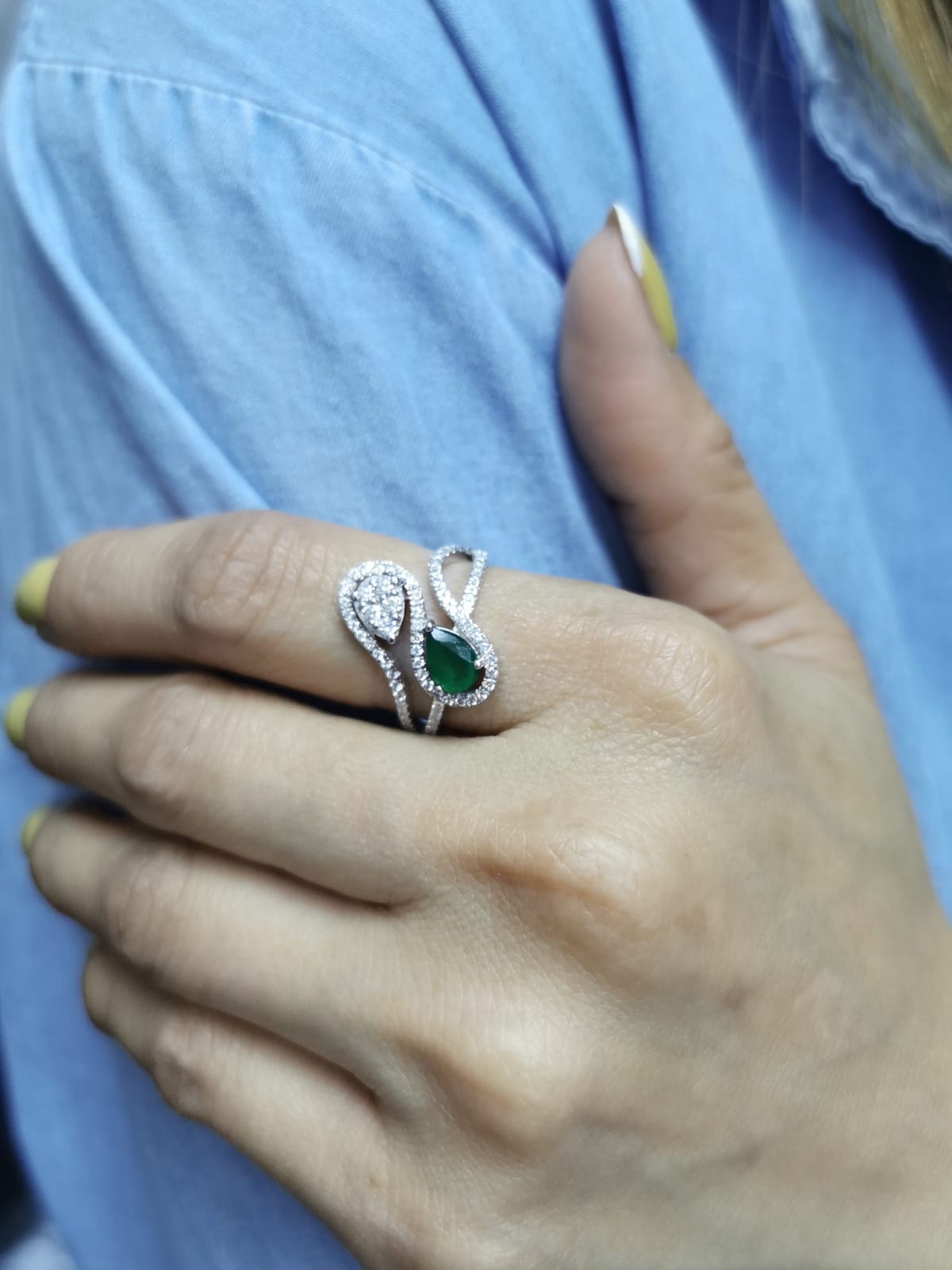 18k gold bypass ring with 0.59 ct pear-cut emerald, pear-shaped diamond cluster, and pavé diamonds, modern asymmetrical design.