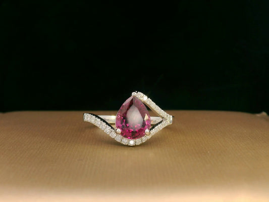 18K white gold rhodolite garnet and diamond wave ring featuring a 1.97ct pear-cut garnet framed by 0.23ct pavé diamonds in an elegant wave design.