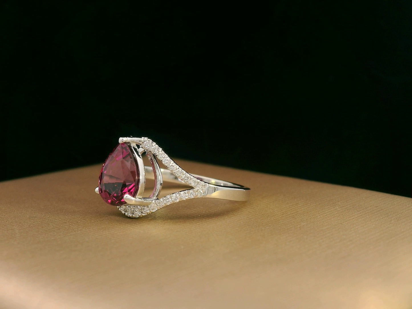 18K white gold rhodolite garnet and diamond wave ring featuring a 1.97ct pear-cut garnet framed by 0.23ct pavé diamonds in an elegant wave design.