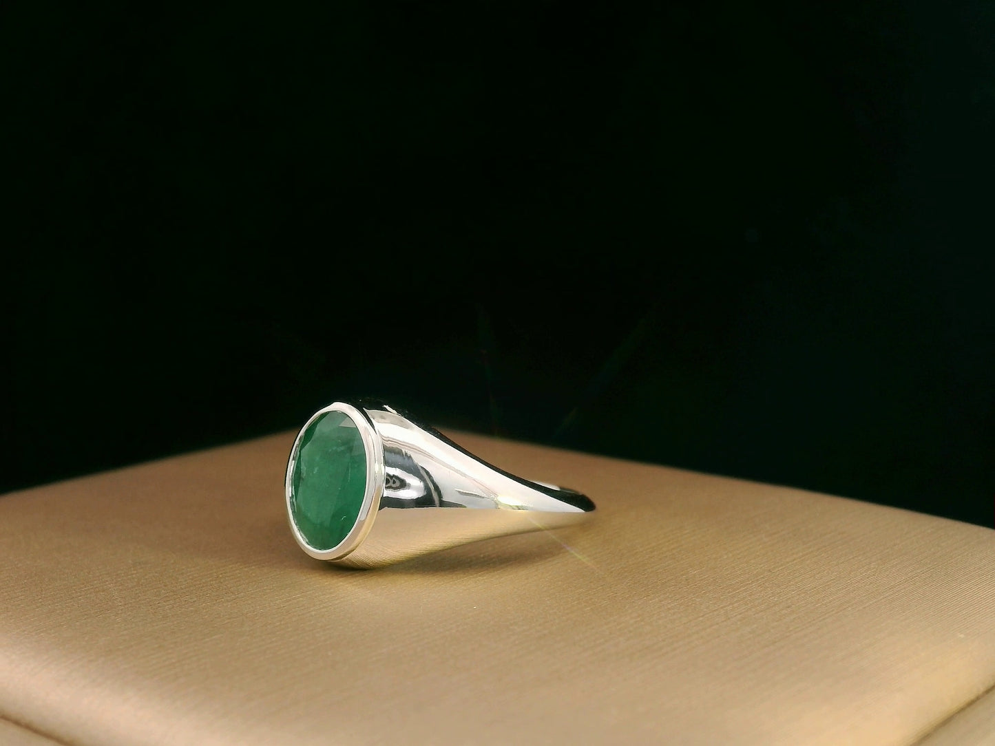 18K white gold men’s signet ring featuring a 1.80ct oval-cut emerald in a sleek bezel setting with a solid tapered band.