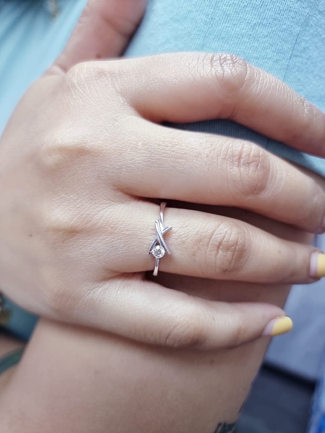 18K white gold ring featuring a 0.12 ct round diamond in a modern tension “X” design, with certificate of authenticity.