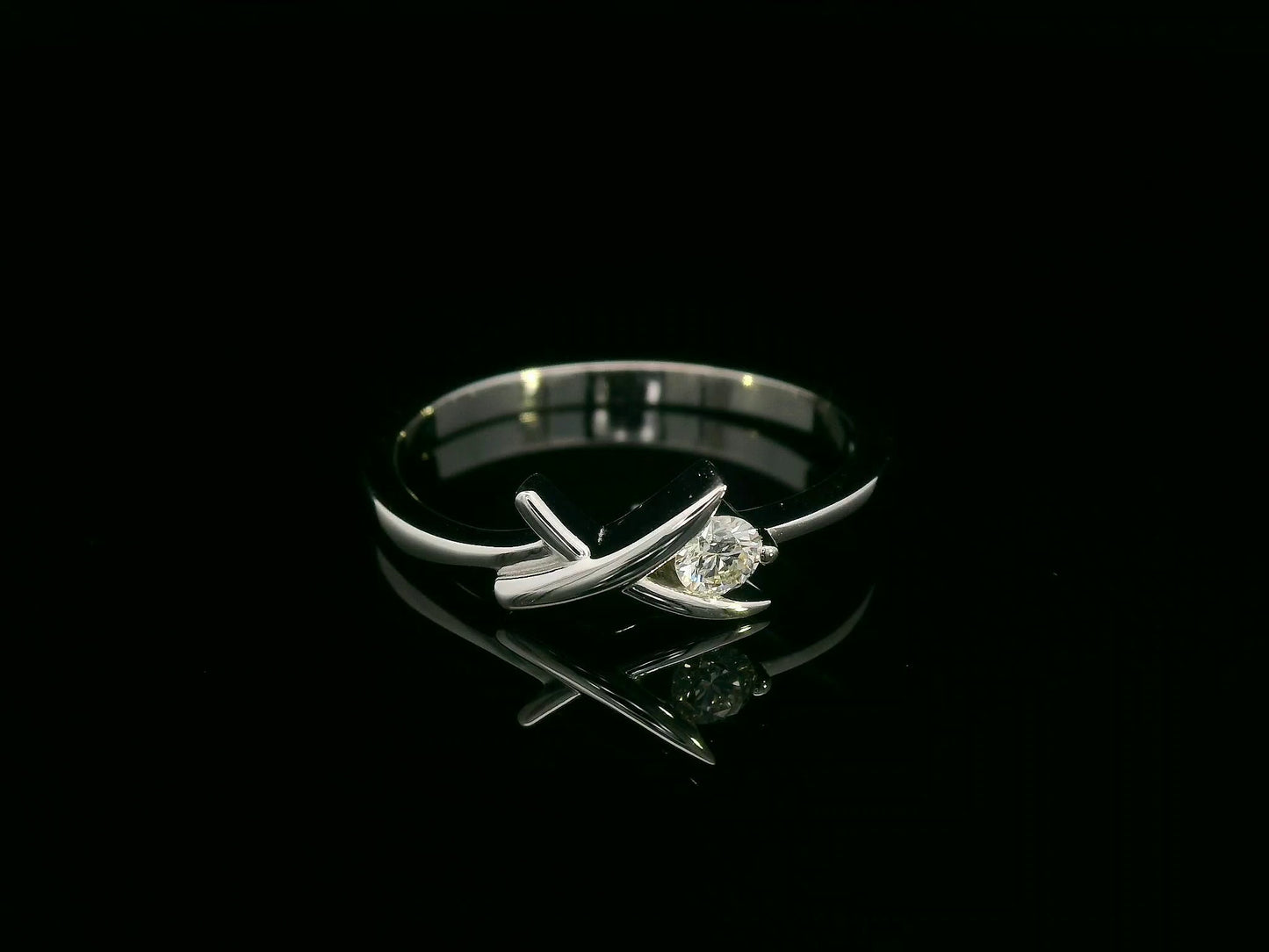 18K white gold ring featuring a 0.12 ct round diamond in a modern tension “X” design, with certificate of authenticity.