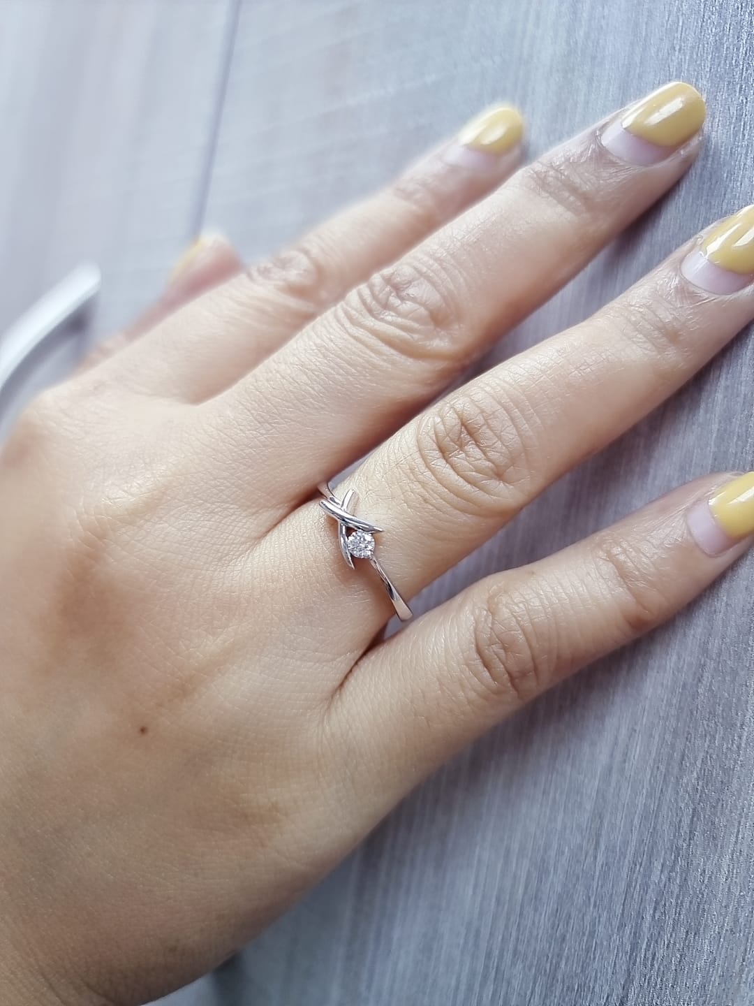 18K white gold ring featuring a 0.12 ct round diamond in a modern tension “X” design, with certificate of authenticity.