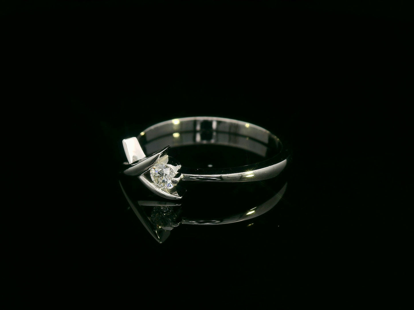 18K white gold ring featuring a 0.12 ct round diamond in a modern tension “X” design, with certificate of authenticity.