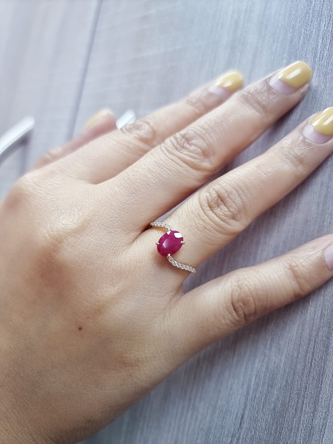 18K yellow gold ruby and diamond wave ring featuring an oval 1.56ct ruby and 0.13ct round diamonds in a flowing wave design.