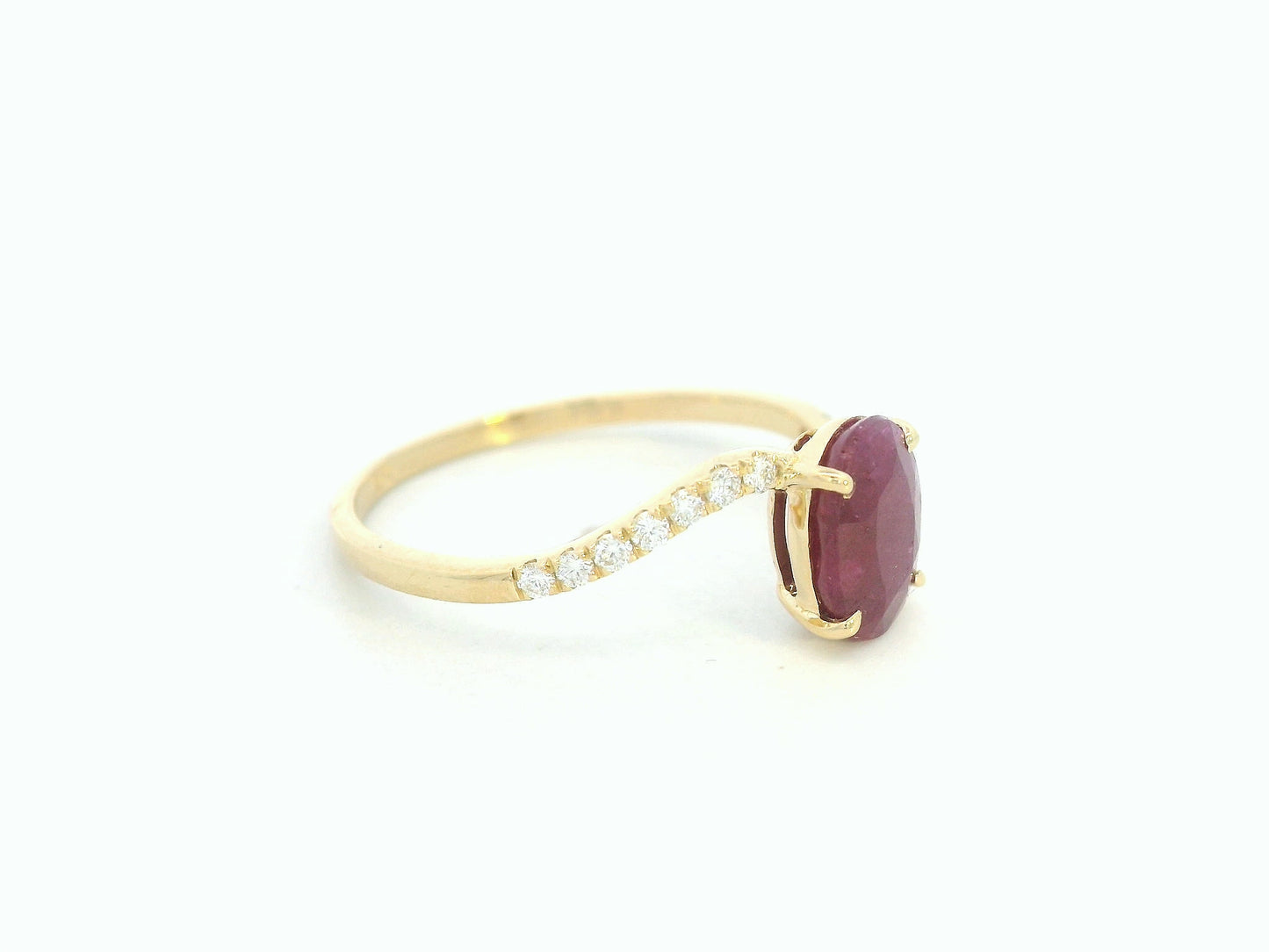 18K yellow gold ruby and diamond wave ring featuring an oval 1.56ct ruby and 0.13ct round diamonds in a flowing wave design.