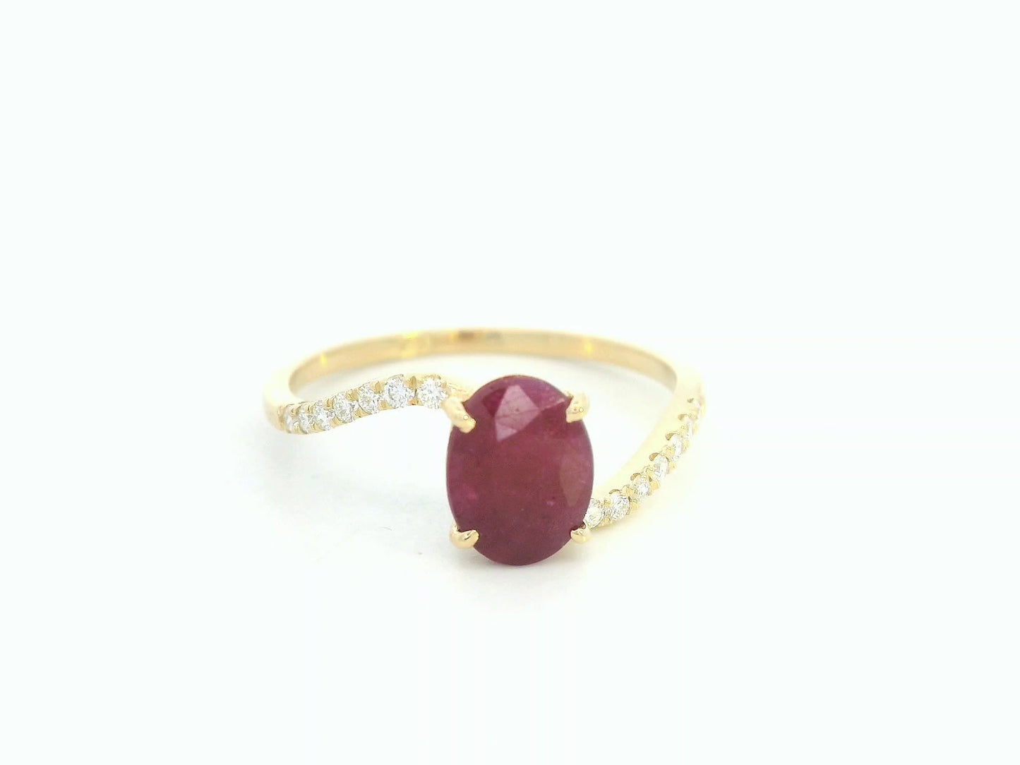 18K yellow gold ruby and diamond wave ring featuring an oval 1.56ct ruby and 0.13ct round diamonds in a flowing wave design.