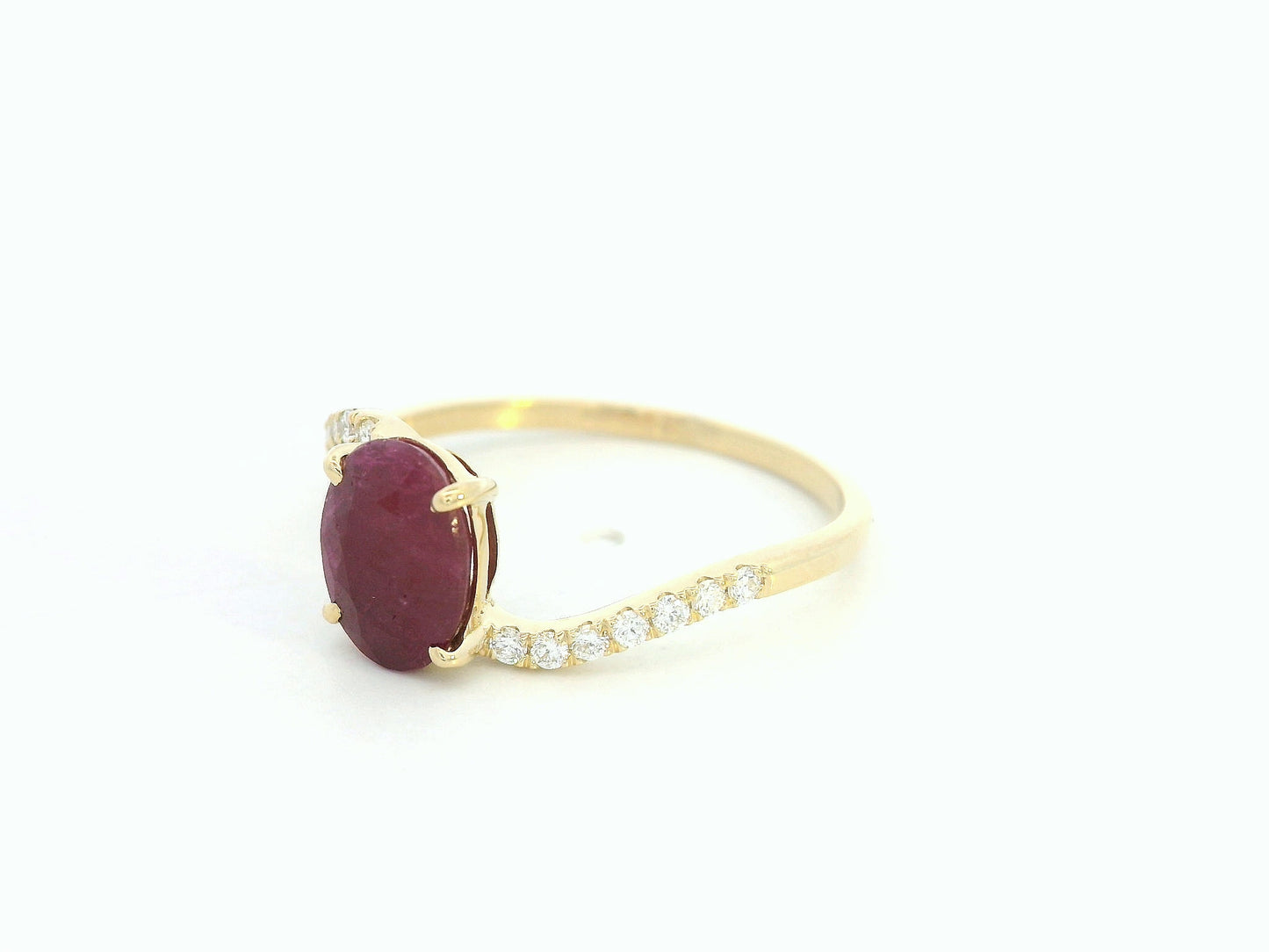18K yellow gold ruby and diamond wave ring featuring an oval 1.56ct ruby and 0.13ct round diamonds in a flowing wave design.