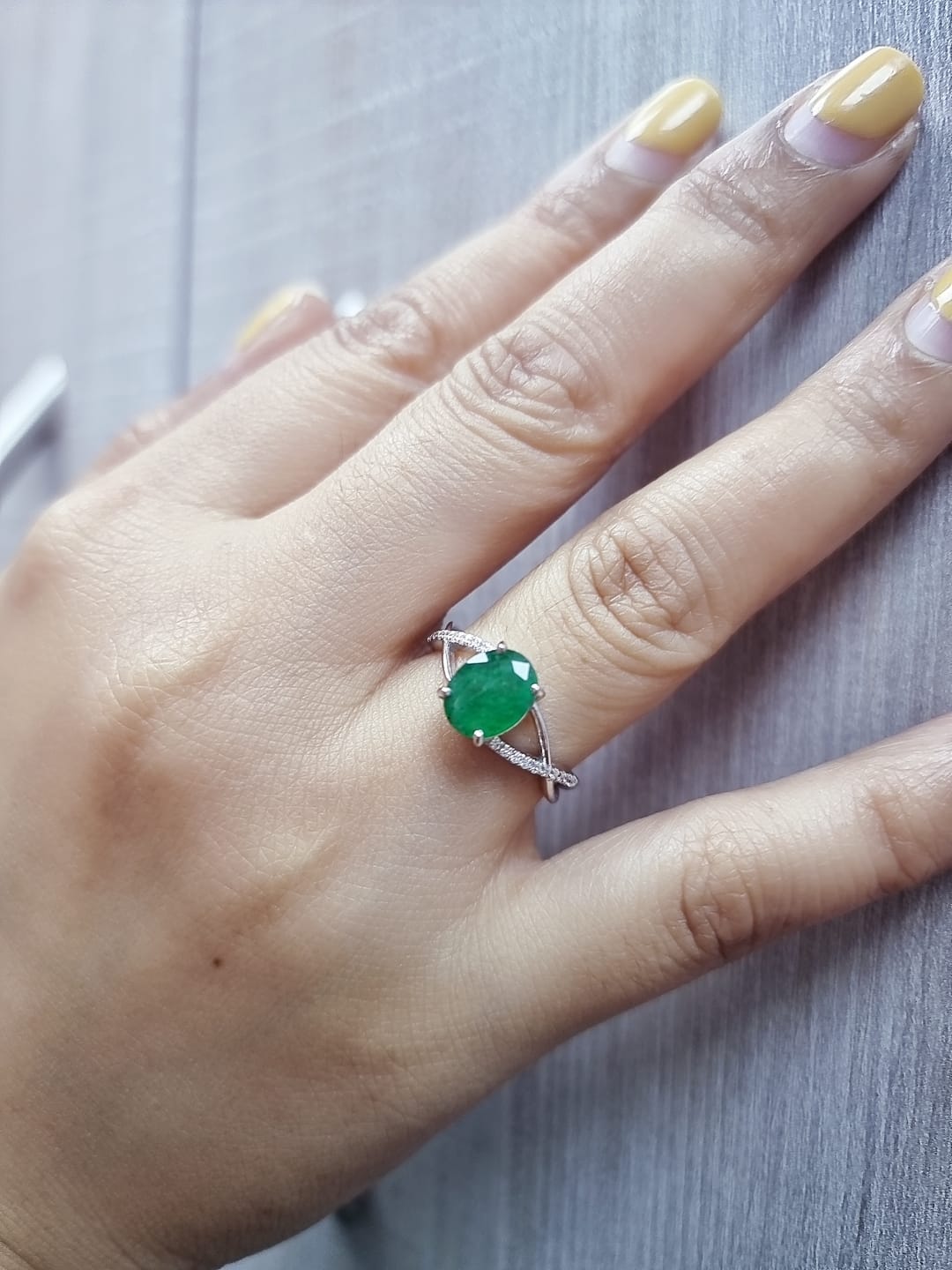 18K white gold ring featuring a 1.59ct oval-cut emerald with 0.10ct diamonds set into a twisted split-shank design.