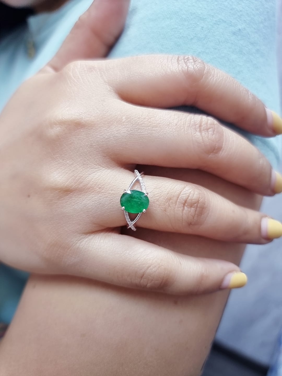 18K white gold ring featuring a 1.59ct oval-cut emerald with 0.10ct diamonds set into a twisted split-shank design.