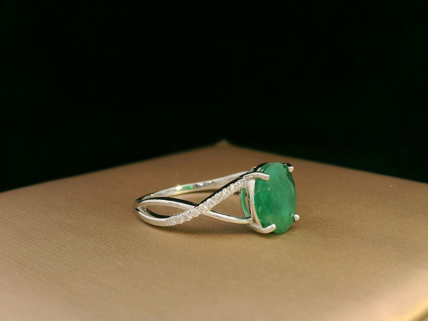 18K white gold ring featuring a 1.59ct oval-cut emerald with 0.10ct diamonds set into a twisted split-shank design.