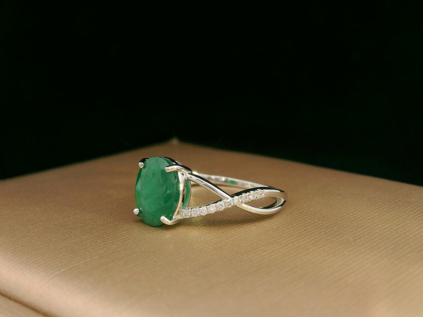 18K white gold ring featuring a 1.59ct oval-cut emerald with 0.10ct diamonds set into a twisted split-shank design.