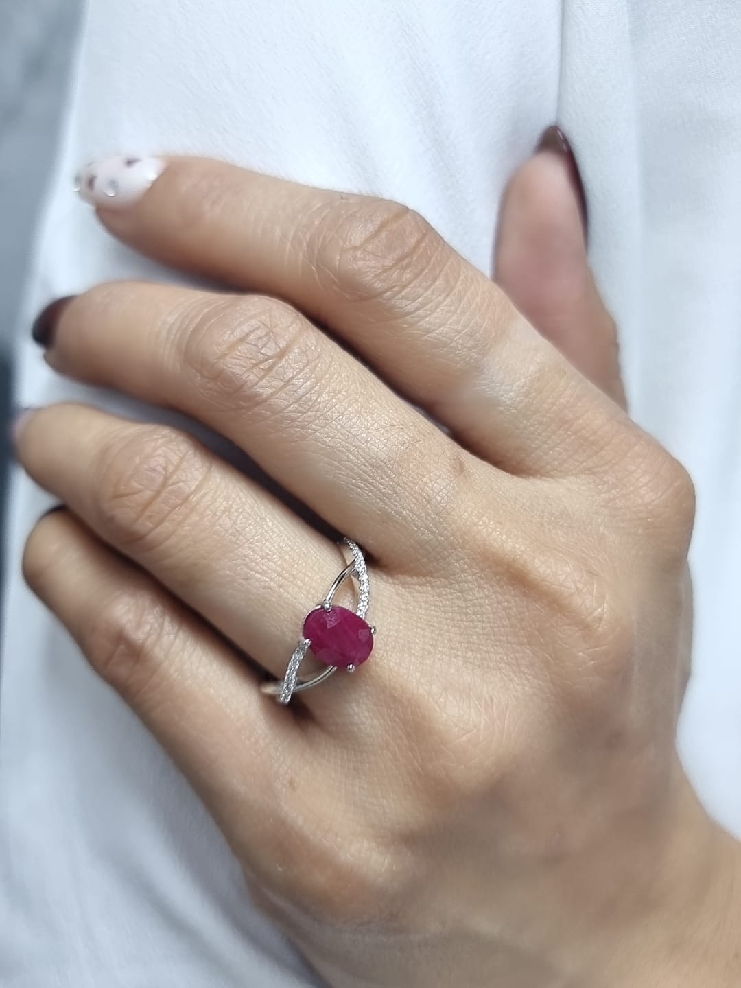 18K white gold ring featuring a 1.47ct oval-cut ruby with 0.11ct diamonds set along a twisted split-shank band.
