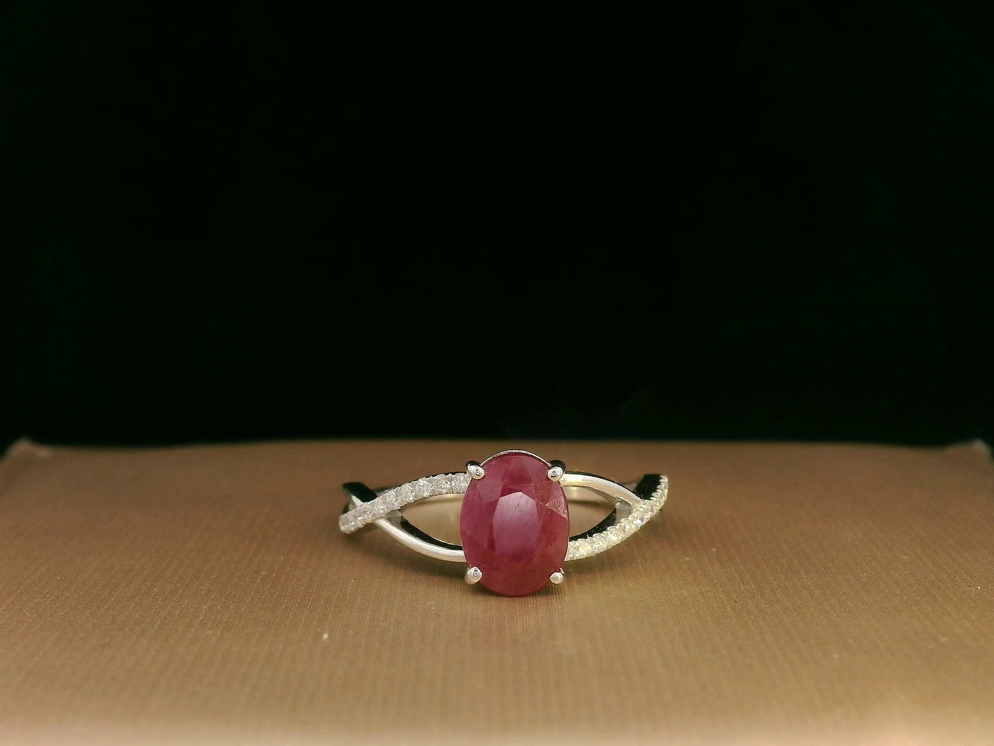18K white gold ring featuring a 1.47ct oval-cut ruby with 0.11ct diamonds set along a twisted split-shank band.