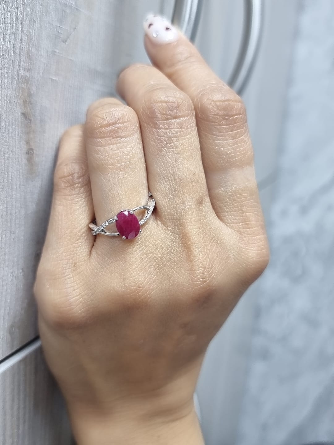 18K white gold ring featuring a 1.47ct oval-cut ruby with 0.11ct diamonds set along a twisted split-shank band.