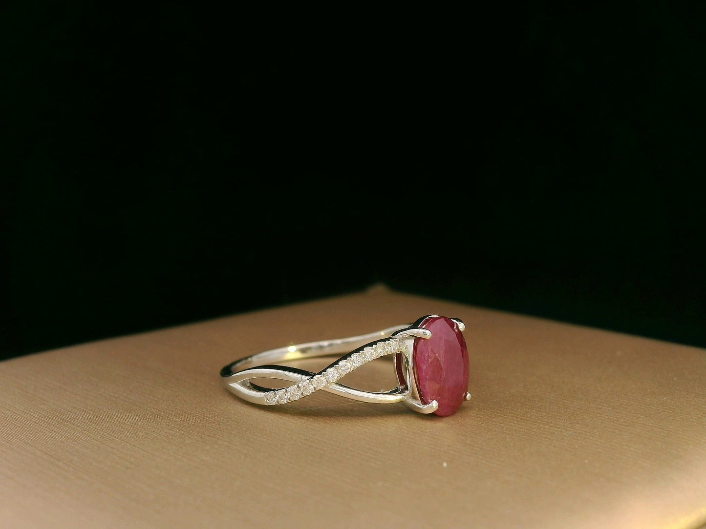 18K white gold ring featuring a 1.47ct oval-cut ruby with 0.11ct diamonds set along a twisted split-shank band.