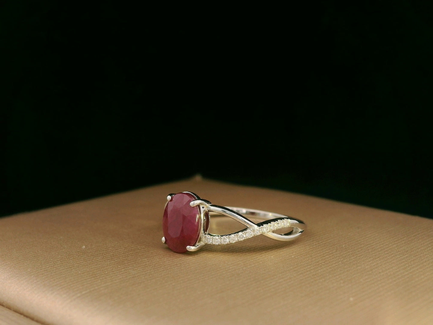 18K white gold ring featuring a 1.47ct oval-cut ruby with 0.11ct diamonds set along a twisted split-shank band.