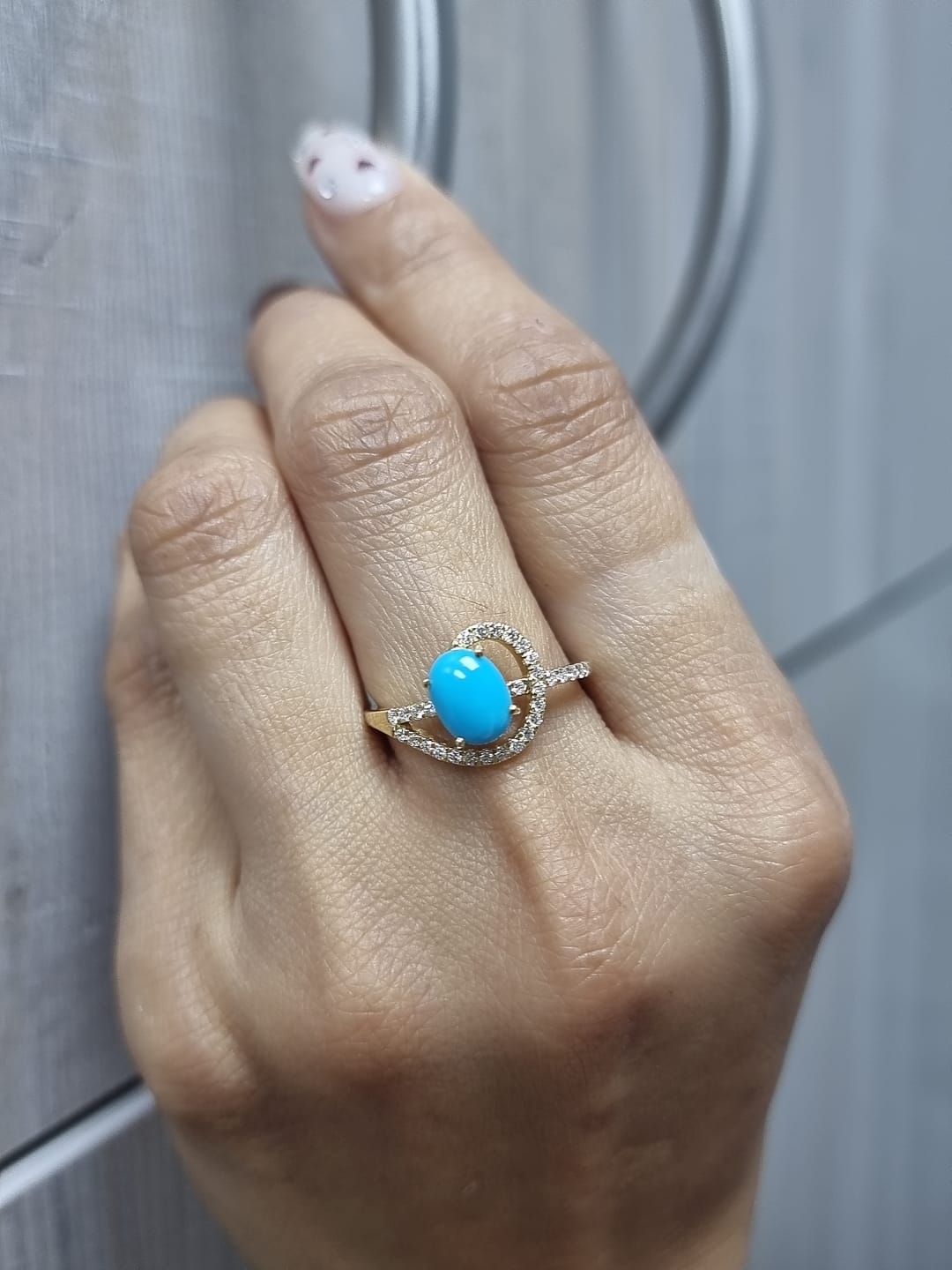 18K yellow gold ring featuring a 1.21ct oval turquoise center with 0.24ct diamonds in an asymmetrical halo and diamond-lined shank.