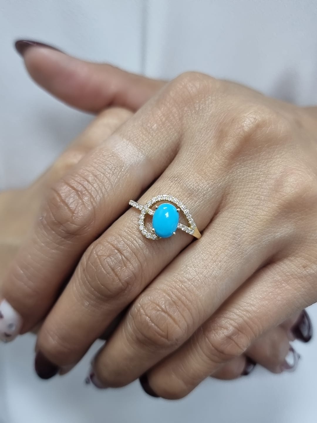 18K yellow gold ring featuring a 1.21ct oval turquoise center with 0.24ct diamonds in an asymmetrical halo and diamond-lined shank.