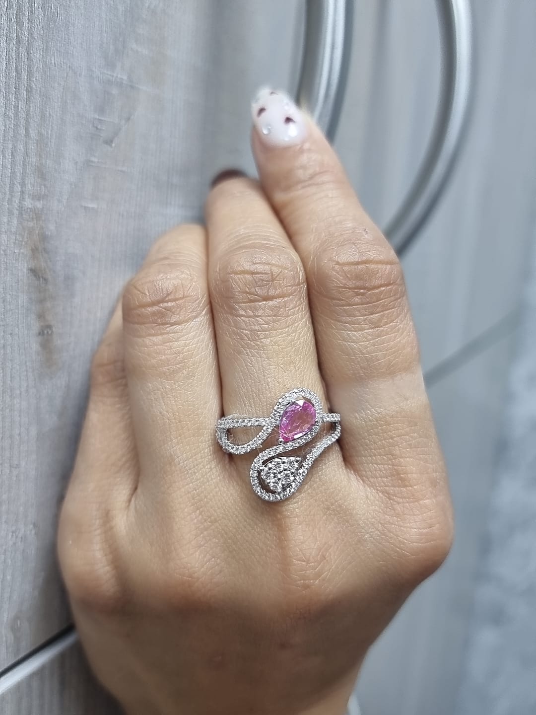 18k white gold ring with 0.74ct pear-shaped pink sapphire and 0.59ct diamonds in a sculptural double-drop design.