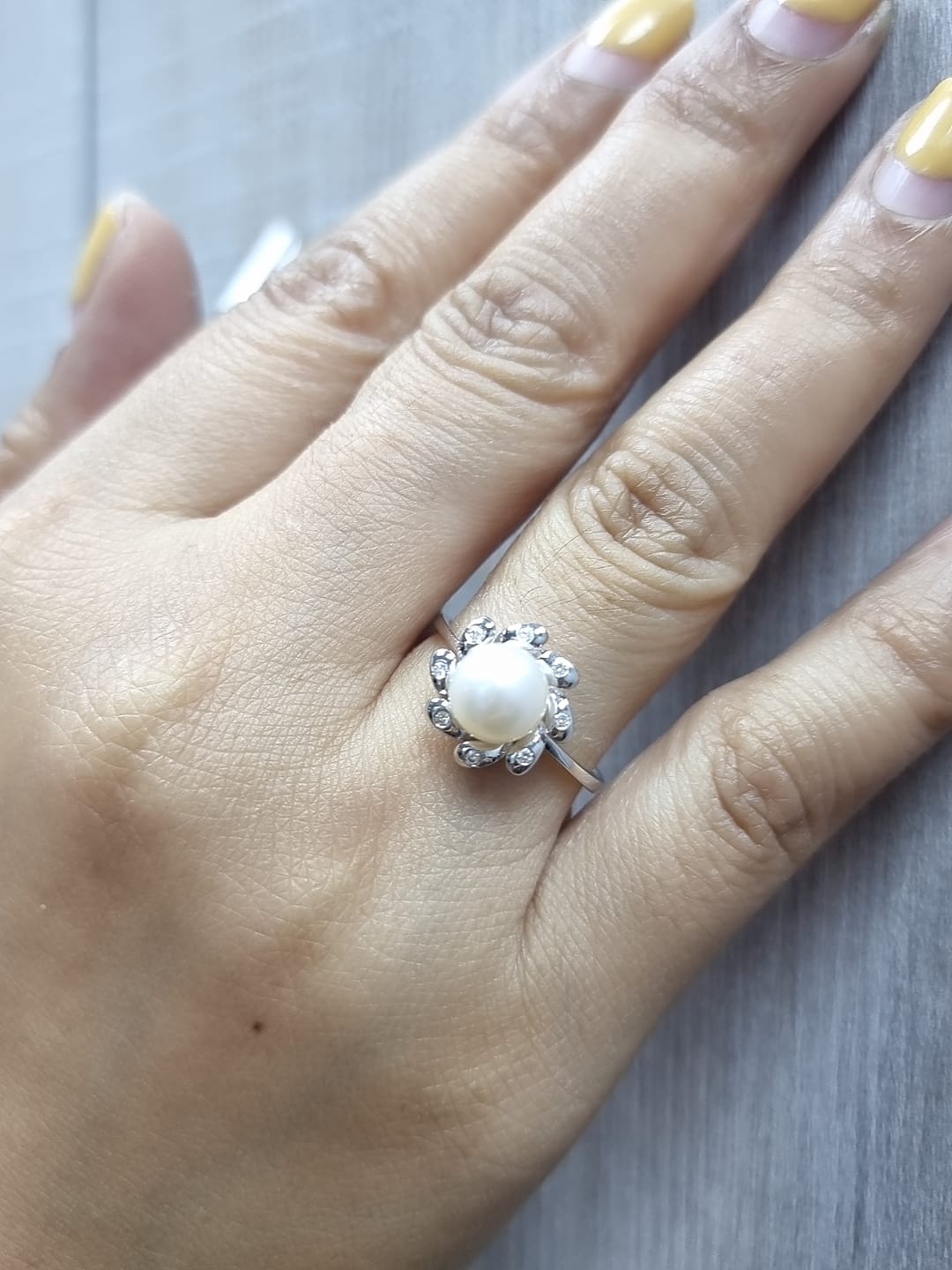 18K white gold ring featuring a luminous freshwater pearl at the center, surrounded by a floral-inspired setting with 0.06ct round diamonds.