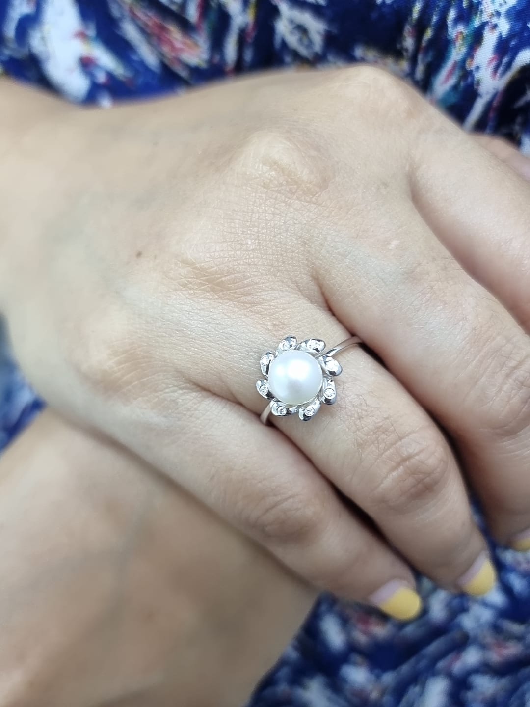 18K white gold ring featuring a luminous freshwater pearl at the center, surrounded by a floral-inspired setting with 0.06ct round diamonds.