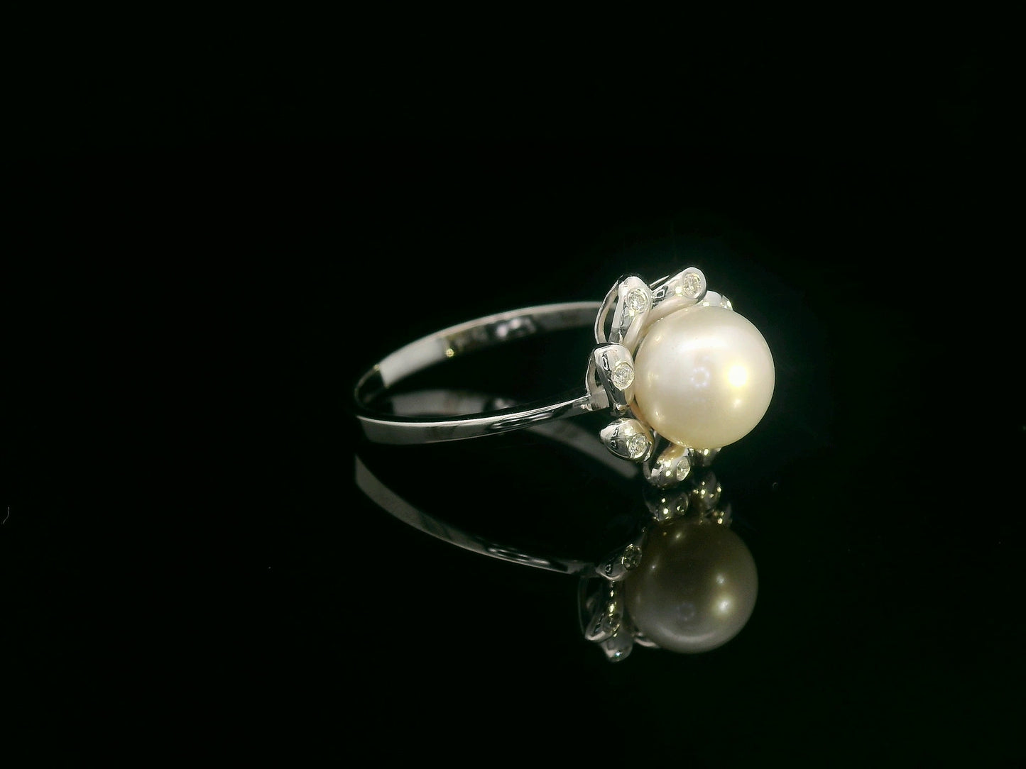 18K white gold ring featuring a luminous freshwater pearl at the center, surrounded by a floral-inspired setting with 0.06ct round diamonds.