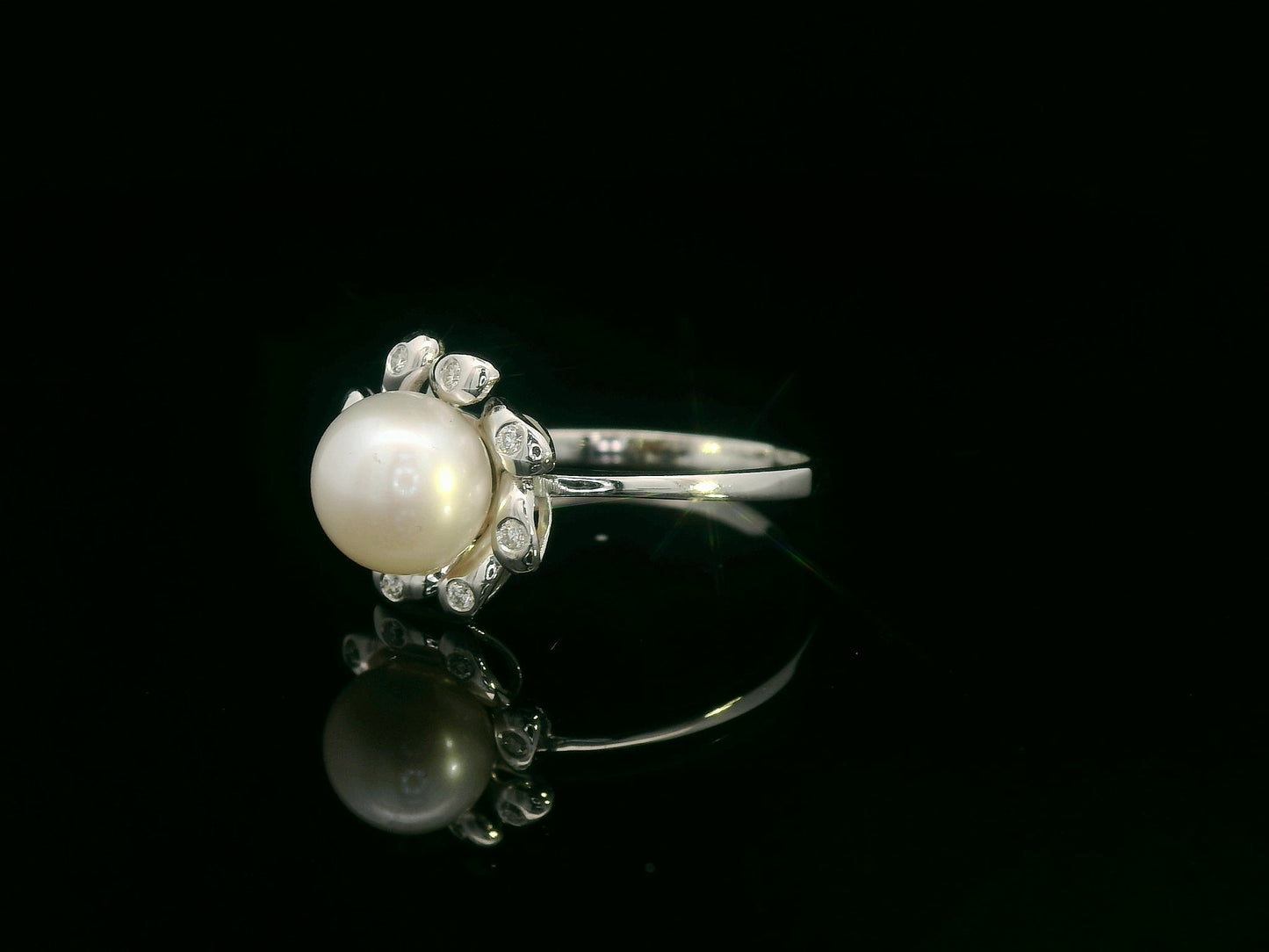 18K white gold ring featuring a luminous freshwater pearl at the center, surrounded by a floral-inspired setting with 0.06ct round diamonds.