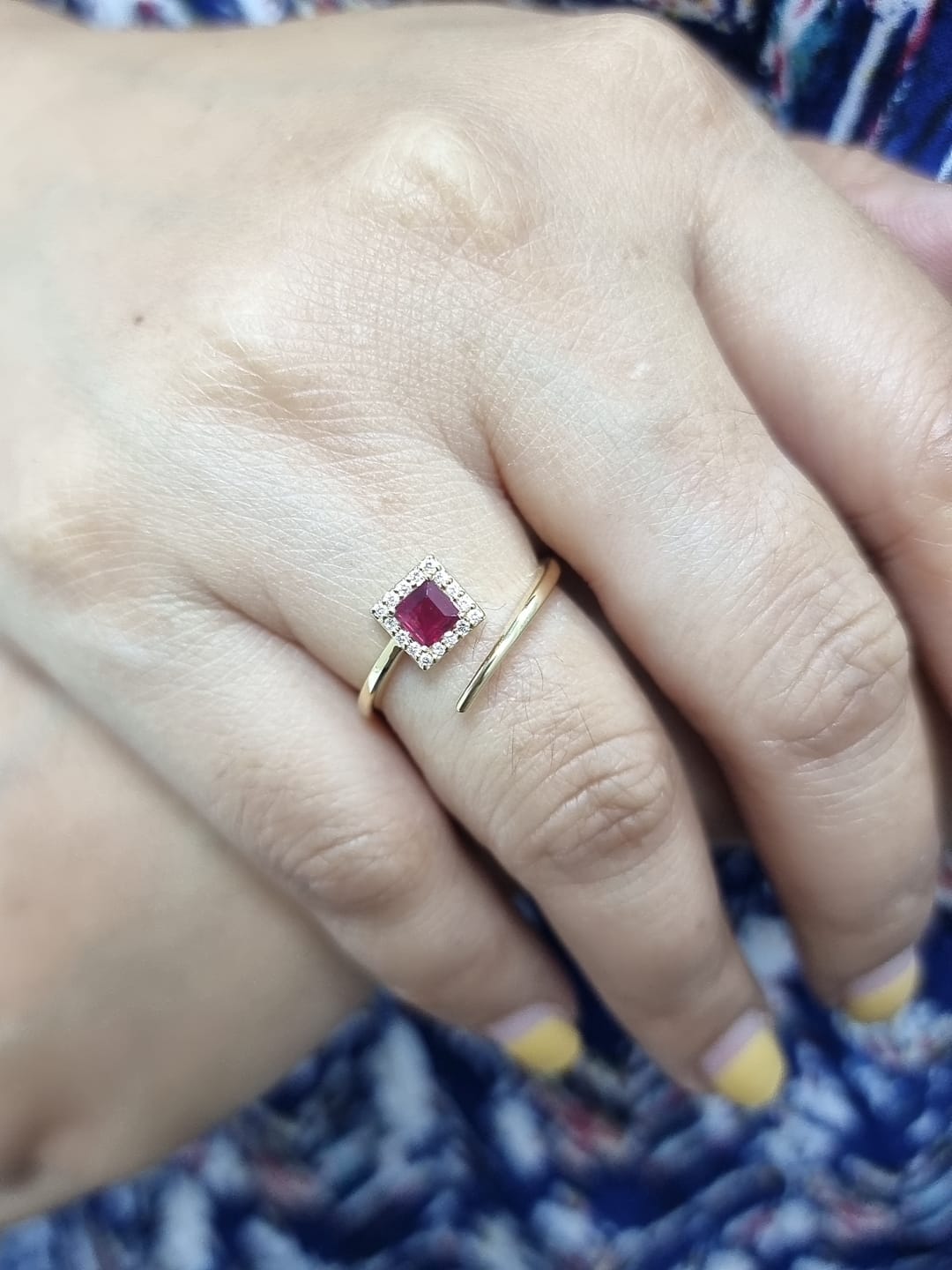 18K yellow gold ring featuring a 0.36ct square-cut ruby with 0.08ct diamonds in a halo setting on a contemporary open-bypass band.