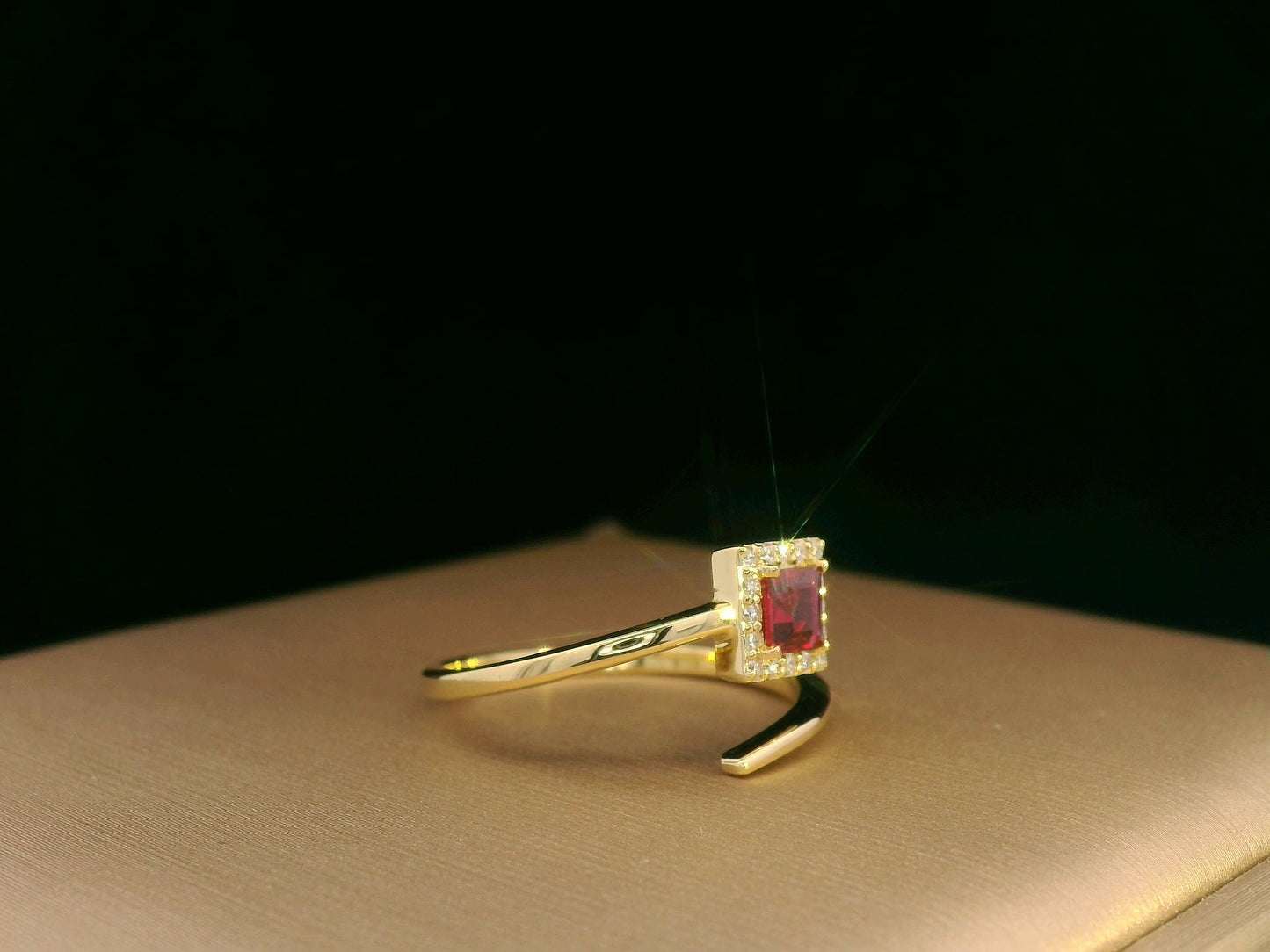 18K yellow gold ring featuring a 0.36ct square-cut ruby with 0.08ct diamonds in a halo setting on a contemporary open-bypass band.