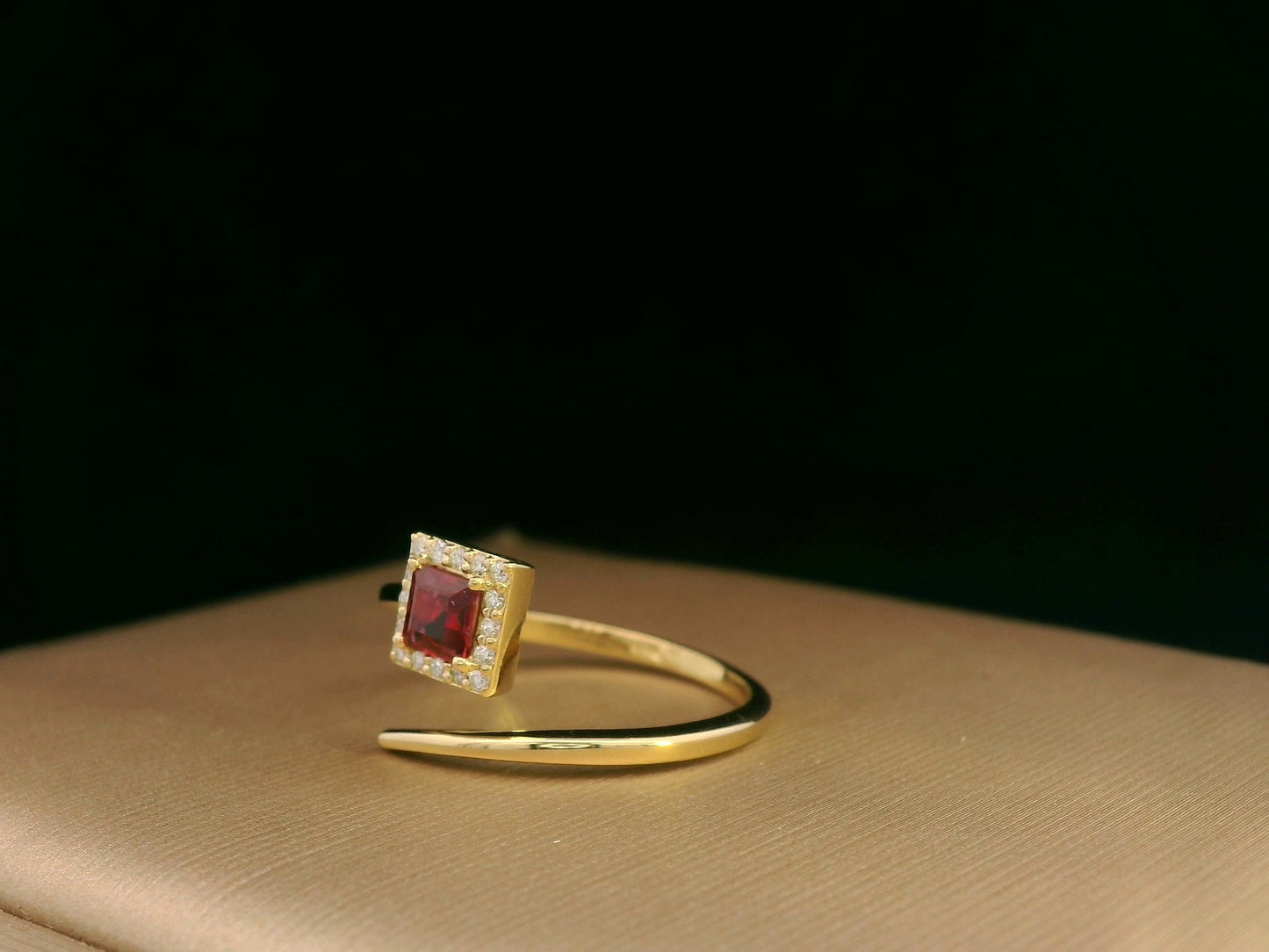 18K yellow gold ring featuring a 0.36ct square-cut ruby with 0.08ct diamonds in a halo setting on a contemporary open-bypass band.