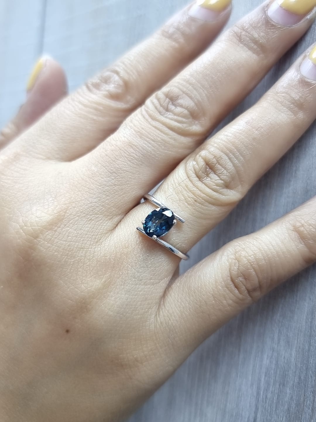 18K white gold bypass ring featuring a 1.49ct oval London Blue Topaz prong-set between gracefully crossing bands.
