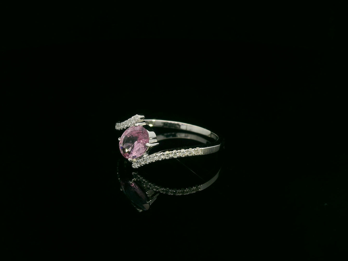 18K white gold bypass ring featuring an oval pink sapphire and pavé-set diamonds in a contemporary open design.