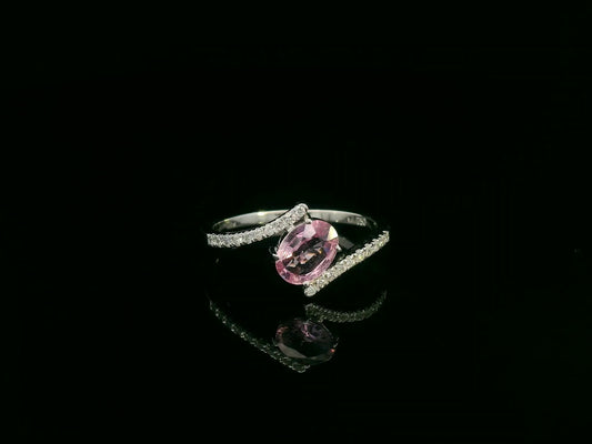 18K white gold bypass ring featuring an oval pink sapphire and pavé-set diamonds in a contemporary open design.
