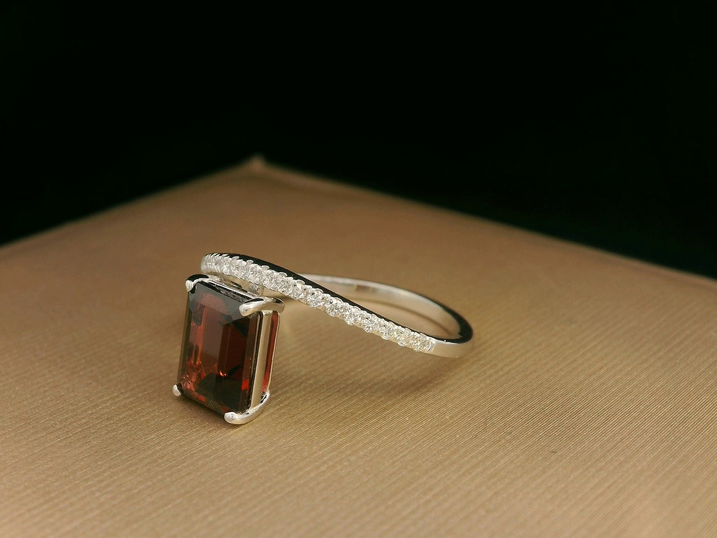 18K white gold bypass ring with emerald-cut garnet and diamond accents