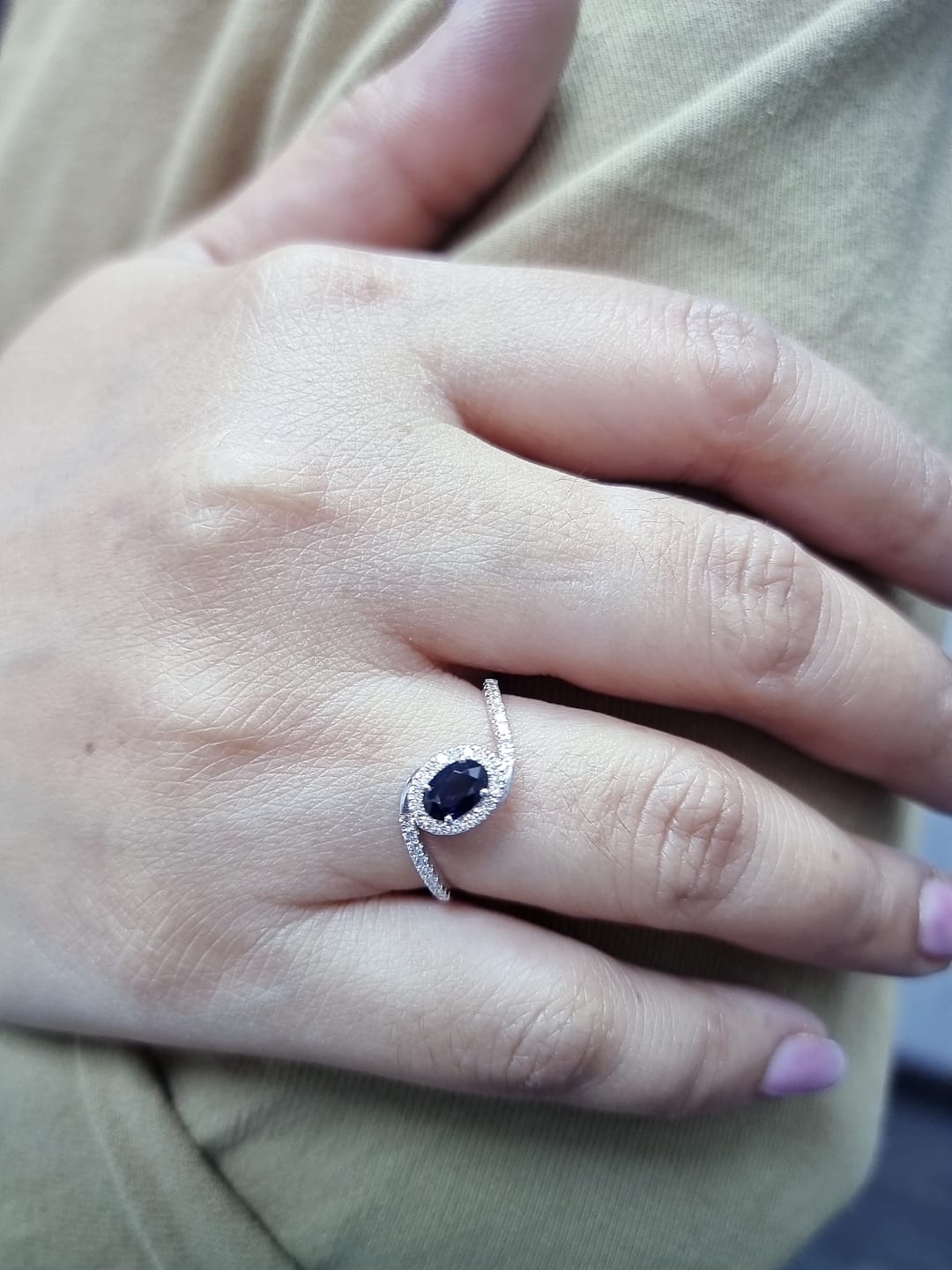 Oval blue sapphire halo ring with pavé diamonds in 18K white gold, bypass design