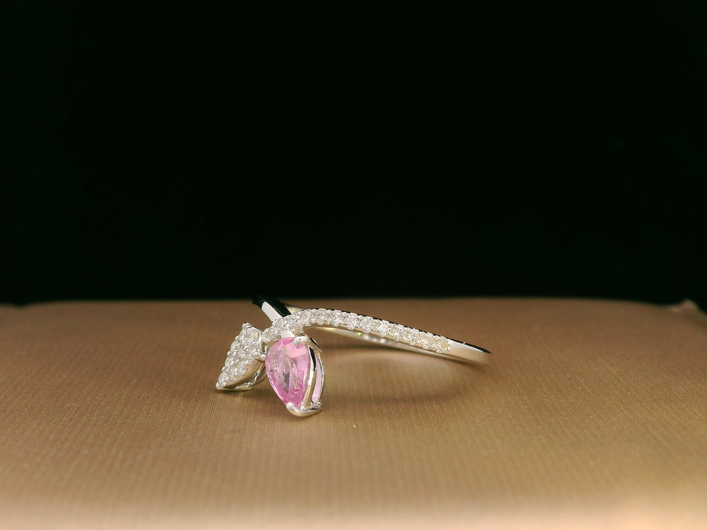 18K white gold bypass ring featuring 0.37ct pear pink sapphire and 0.15ct diamonds in a modern pear motif design.