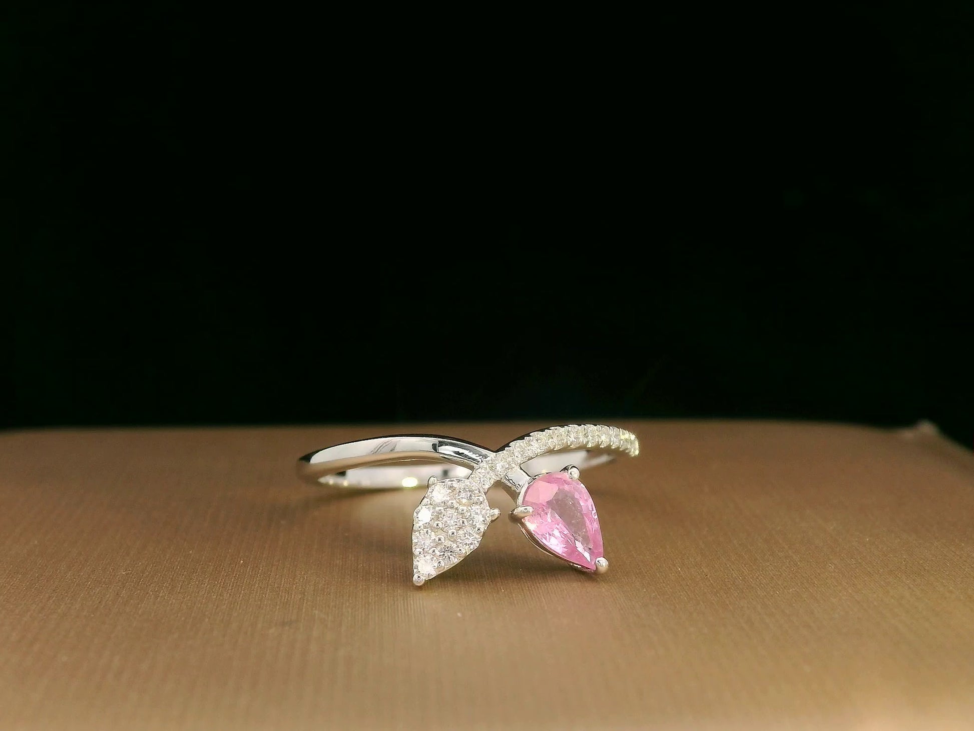 18K white gold bypass ring featuring 0.37ct pear pink sapphire and 0.15ct diamonds in a modern pear motif design.