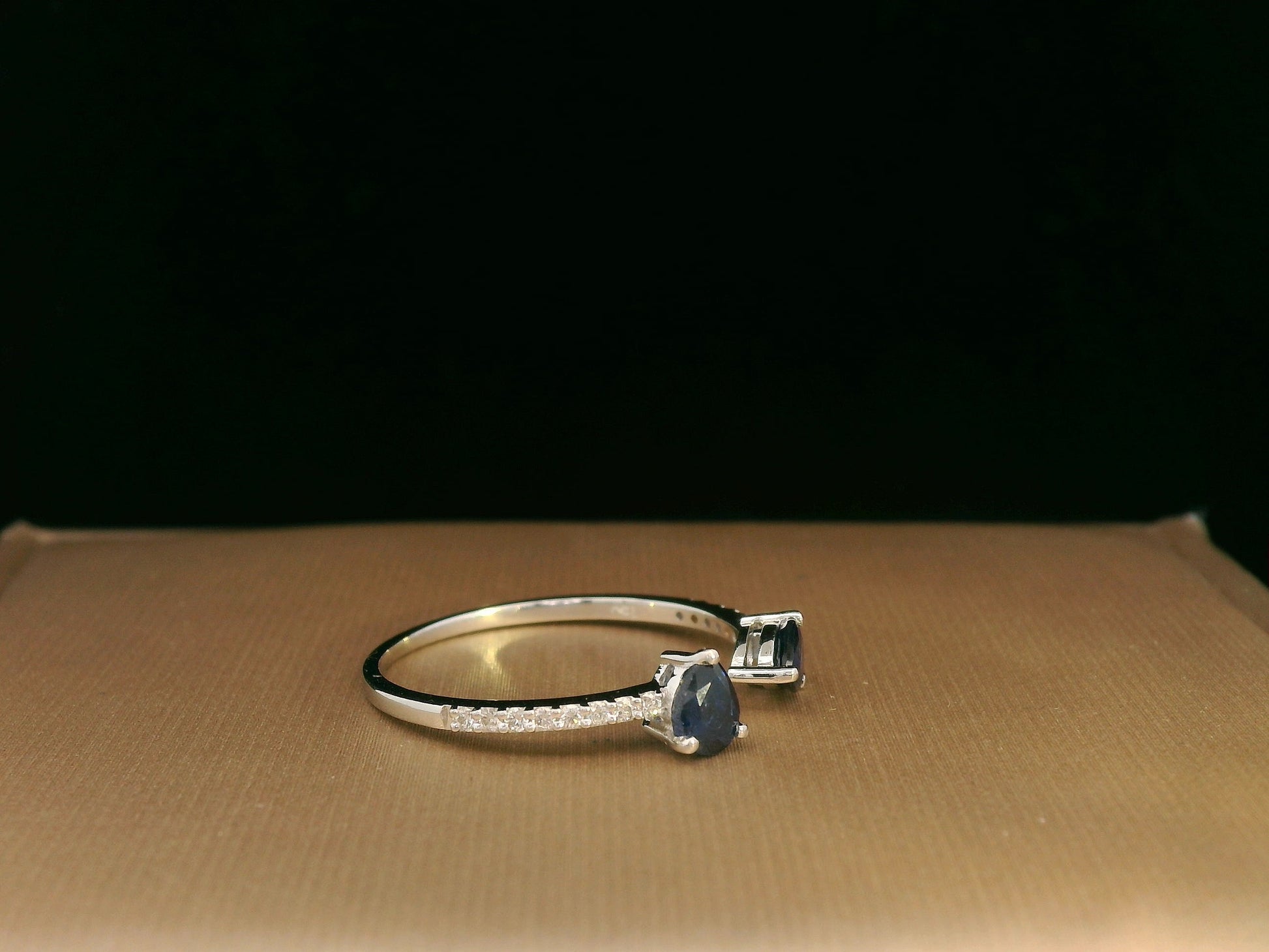 18K white gold open cuff ring with two teardrop-cut blue sapphires (0.70 carat) and 0.10 carat diamond pavé, modern minimalist design