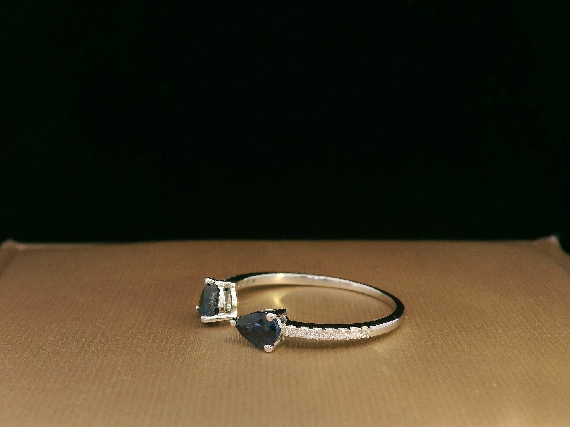 18K white gold open cuff ring with two teardrop-cut blue sapphires (0.70 carat) and 0.10 carat diamond pavé, modern minimalist design