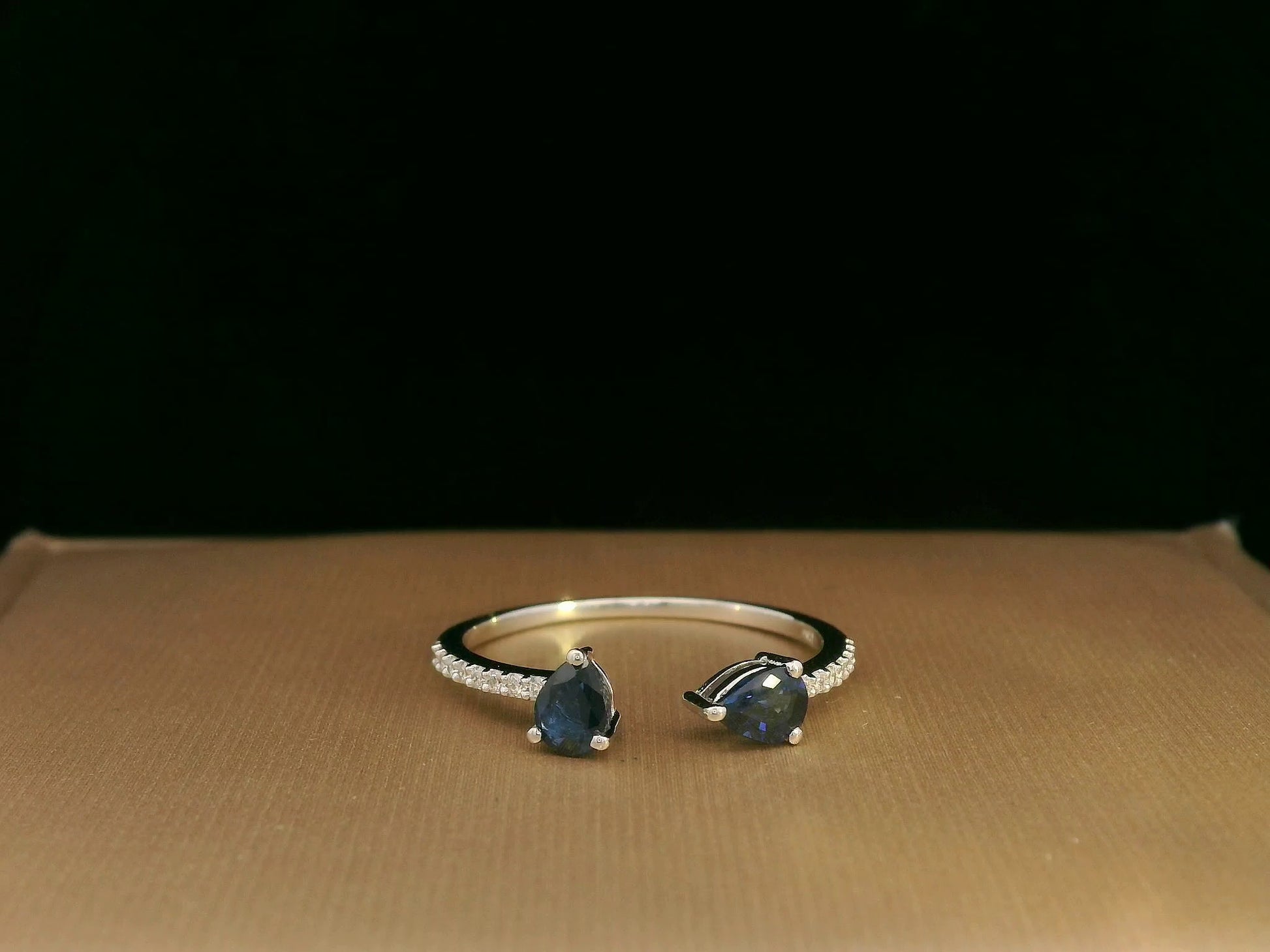 18K white gold open cuff ring with two teardrop-cut blue sapphires (0.70 carat) and 0.10 carat diamond pavé, modern minimalist design