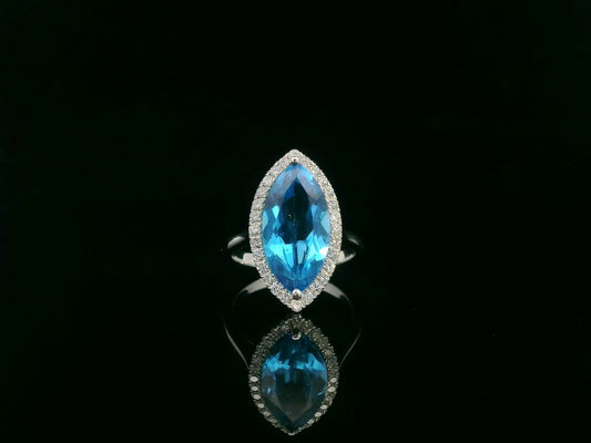 Marquise-cut blue topaz ring with diamond halo in 18K gold.