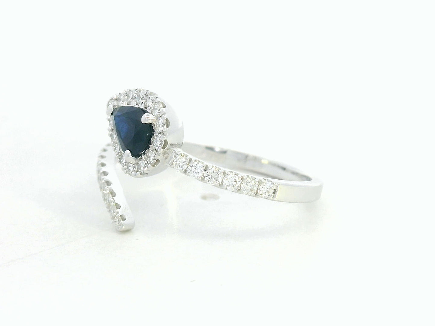 18K white gold bypass ring with pear-shaped blue sapphire and diamond halo by Emirates Diamonds