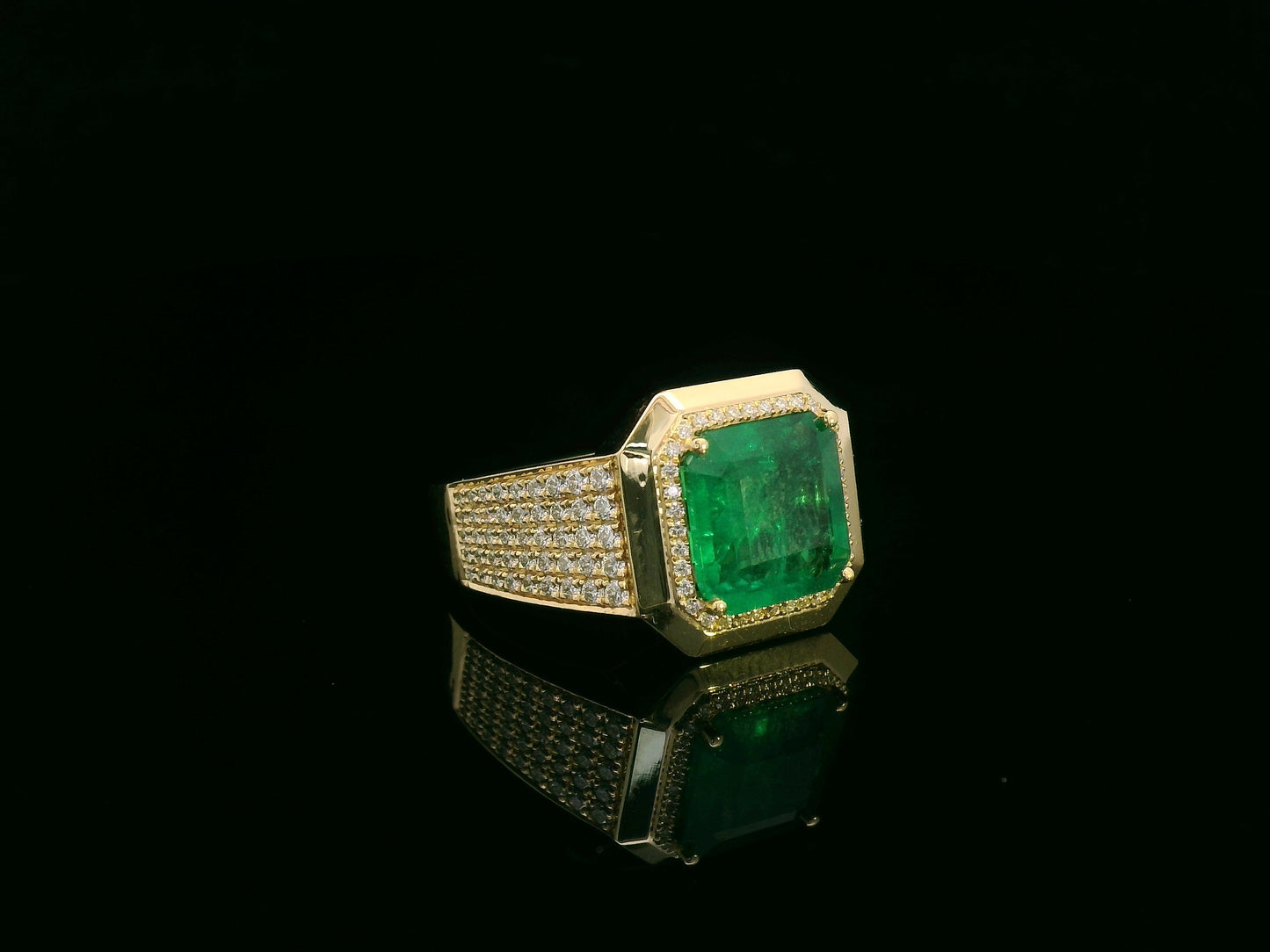 Men’s 18K yellow gold emerald and diamond statement ring featuring a 3.30 carat emerald with diamond halo and wide pavé band by Emirates Diamonds