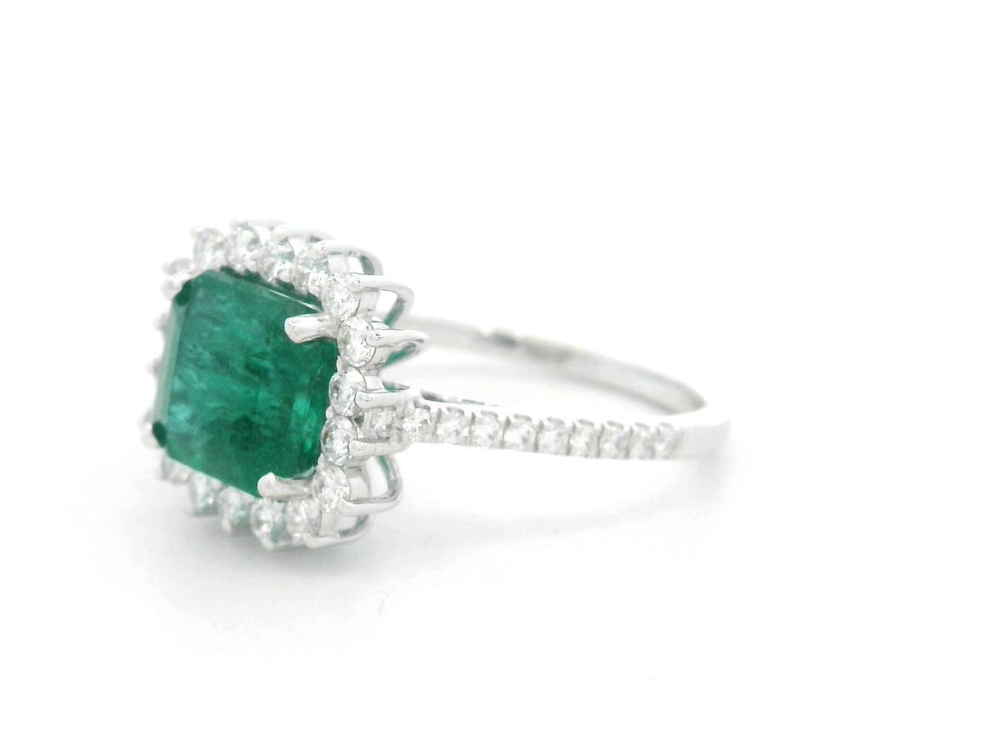 Emerald and diamond halo ring in 18K white gold featuring a 2.12 carat emerald and pavé diamond band by Emirates Diamonds