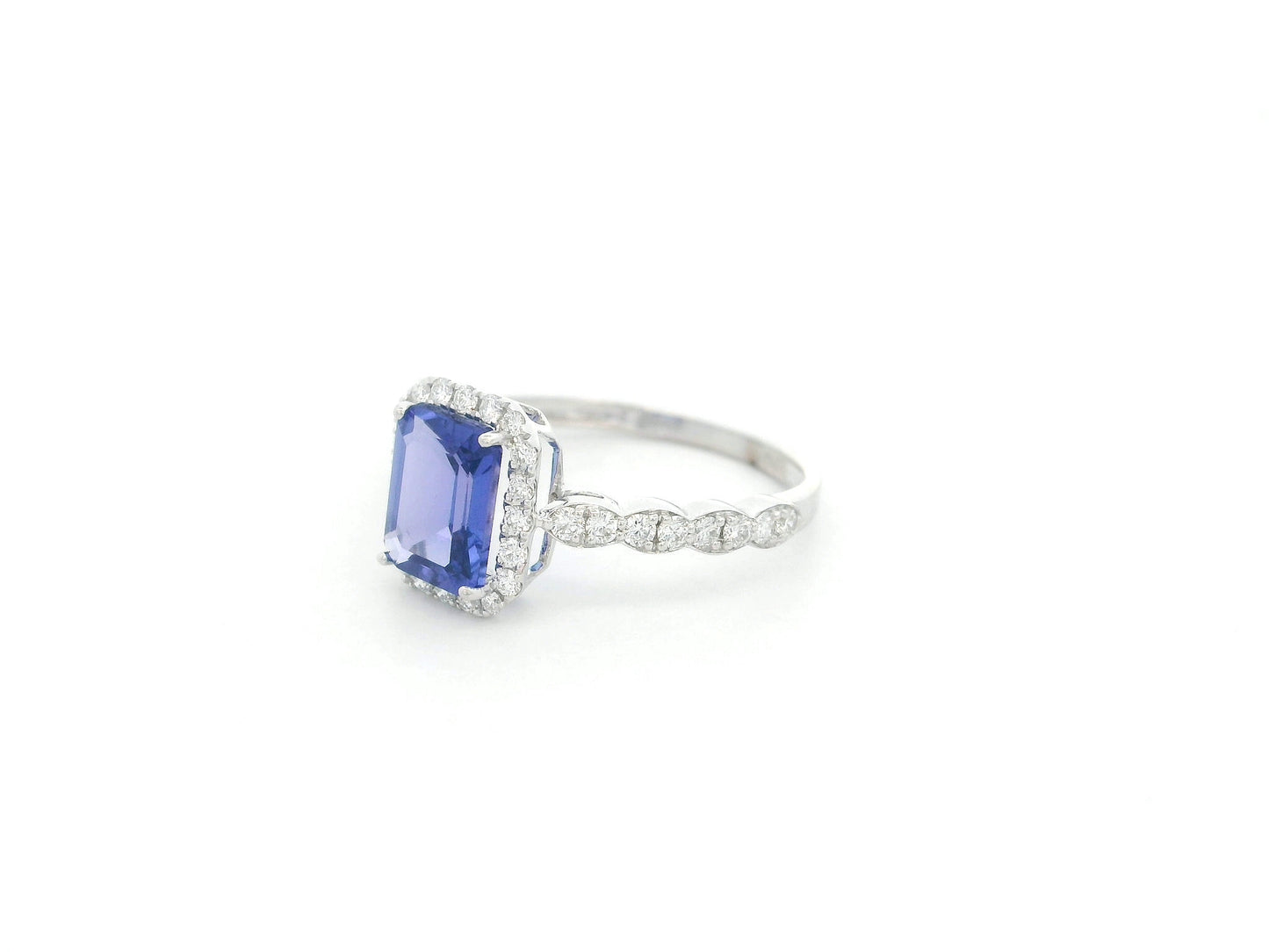 Emerald cut tanzanite halo ring in 18K white gold with marquise diamond band