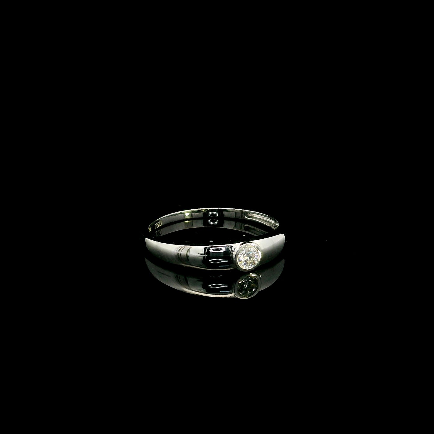 18K white gold bezel set solitaire diamond ring featuring a 0.11 carat natural round brilliant diamond with a smooth polished band.