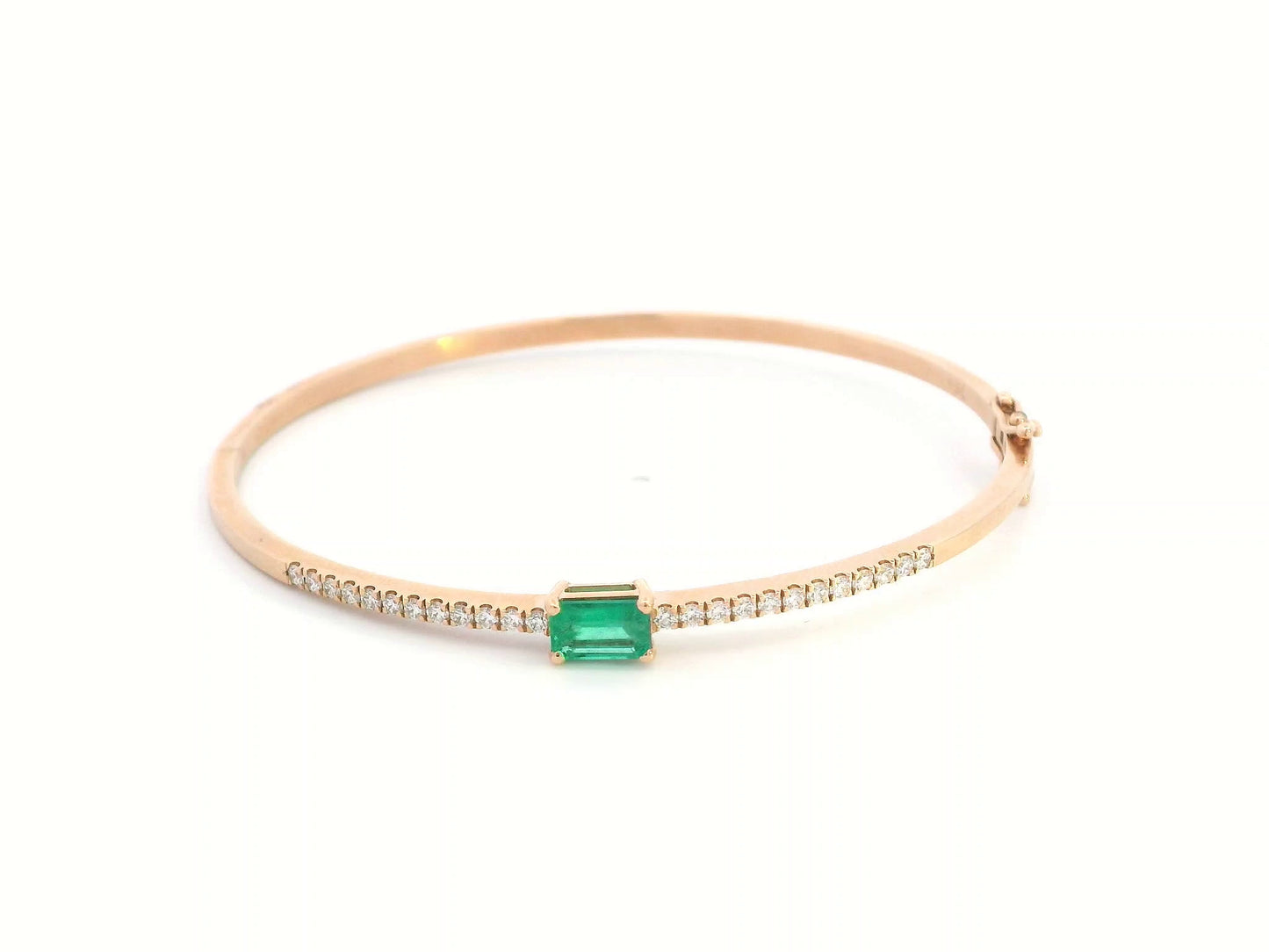 18K gold bangle with emerald-cut 0.50 carat green emerald and 0.34 carat round diamonds in a hinged bracelet design.