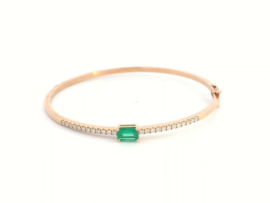 18K gold bangle with emerald-cut 0.50 carat green emerald and 0.34 carat round diamonds in a hinged bracelet design.